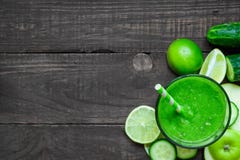 Grön sund smoothie i ett exponeringsglas med spenat, äpplet, gurkan och limefrukt med ett sugrör över den lantliga trätabellen arkivfoton Grön sund smoothie i ett exponeringsglas med spenat, äpplet, gurkan och limefrukt med ett sugrör över den lantliga trätabellen arkivfoton