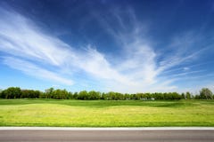 Grön äng och blå himmel med asfaltvägen arkivbild Grön äng och blå himmel med asfaltvägen arkivbild