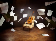 Guitar on an old chair with flying music sheets