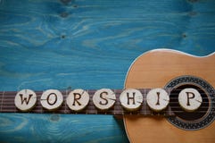 Guitar on teal wood with the word: WORSHIP
