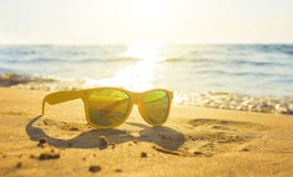 Gula exponeringsglas havssanden, solglasögon med härligt havslandskap solglasögon reflekteras i det guld- blöter sand som royaltyfri fotografi Gula exponeringsglas havssanden, solglasögon med härligt havslandskap solglasögon reflekteras i det guld- blöter sand som royaltyfri fotografi