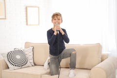 Gullig pojke med mikrofonen p? soffan i rum royaltyfri bild Gullig pojke med mikrofonen p? soffan i rum royaltyfri bild