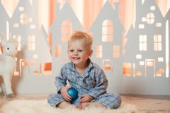 Gullig pys för blont hår i sleepwear nära hus för julleksakpapper royaltyfri fotografi Gullig pys för blont hår i sleepwear nära hus för julleksakpapper royaltyfri fotografi