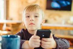Gullig pys som hemma spelar lekar på smartphonen royaltyfri fotografi Gullig pys som hemma spelar lekar på smartphonen royaltyfri fotografi