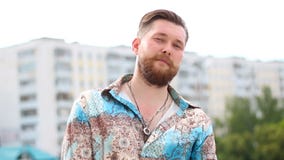 Gut aussehender Mann, der Horngeste auf unfocused städtischem Hintergrund macht stock video footage Gut aussehender Mann, der Horngeste auf unfocused städtischem Hintergrund macht stock video footage