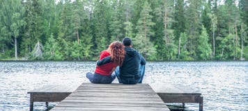 Guy And A Girl Sit Hugging On The Pier Of A Beautiful Lake. The Concept Of Love, The Summer Mood , Banner Stock Image