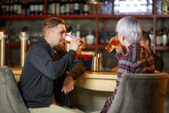 A guy with a beard and a girl with short blond hair, sitting in a bar and drinking beer. Indoors stock image A guy with a beard and a girl with short blond hair, sitting in a bar and drinking beer. Indoors stock image
