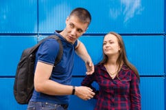 Guy in blue T-shirt and backpack on his back next to girl dressed in blue jeans and plaid shirt against blue wall royalty free stock photos Guy in blue T-shirt and backpack on his back next to girl dressed in blue jeans and plaid shirt against blue wall royalty free stock photos