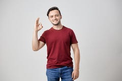 The guy dressed in burgundy t-shirt feels glad and shows sign ok with his fingers stock photo The guy dressed in burgundy t-shirt feels glad and shows sign ok with his fingers stock photo