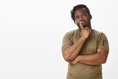 Guy making importrant decision. Portrait of smart thoughtful african boyfriend in military t-shirt, frowning and holding stock photo Guy making importrant decision. Portrait of smart thoughtful african boyfriend in military t-shirt, frowning and holding stock photo