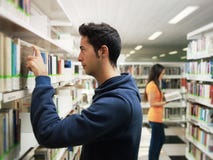 Guy taking book from shelf in library stock photos Guy taking book from shelf in library stock photos