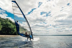 The guy in the waggon swims on the windsurf on lake stock photo The guy in the waggon swims on the windsurf on lake stock photo