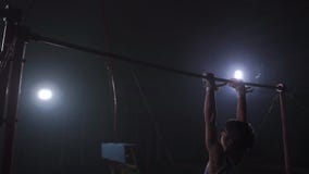 Gymnast exercises on high horizontal bar HD slow-motion video. Athlete training gymnastics skills and performing giant