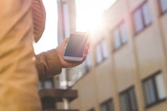 Gå och bärande smartphone för ung kvinna i solsken Stäng sig upp av den hållande mobiltelefonen för flickan i hand fotografering för bildbyråer Gå och bärande smartphone för ung kvinna i solsken Stäng sig upp av den hållande mobiltelefonen för flickan i hand fotografering för bildbyråer