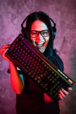 H?rlig yrkesm?ssig Gamerflicka med tangentbordet Exponeringsglas och le f?r tillf?llig gullig Geek b?rande Cybere-sport internet royaltyfri fotografi H?rlig yrkesm?ssig Gamerflicka med tangentbordet Exponeringsglas och le f?r tillf?llig gullig Geek b?rande Cybere-sport internet royaltyfri fotografi