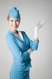 Hôtesse avec du charme In Blue Uniform se dirigeant sur Gray Bac photos libres de droits Hôtesse avec du charme In Blue Uniform se dirigeant sur Gray Bac photos libres de droits