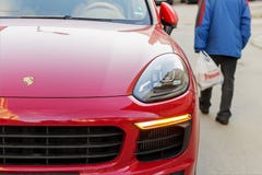 Ha vestito male le passeggiate dell'uomo senior giù la via dopo un'automobile rossa di Porsche Concetto di lusso e di povertà Con fotografia stock libera da diritti Ha vestito male le passeggiate dell'uomo senior giù la via dopo un'automobile rossa di Porsche Concetto di lusso e di povertà Con fotografia stock libera da diritti