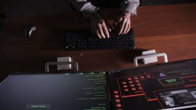 Hacker hands cracking code using computers in dark room.