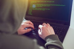 Hackers programmer look on screen and writes the program code hack information and user account stock images Hackers programmer look on screen and writes the program code hack information and user account stock images