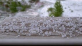 Hail Outside the Window. Pieces of hail lie on the windowsill behind a plastic window.