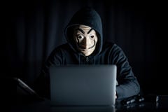 Hakkermens in geheimzinnigheid masker die laptop met behulp van stock afbeelding Hakkermens in geheimzinnigheid masker die laptop met behulp van stock afbeelding
