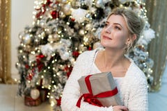 Half lengteportret van mooi jong blondemeisje in het witte sweater stellen met gift dichtbij de Kerstboom royalty-vrije stock foto's Half lengteportret van mooi jong blondemeisje in het witte sweater stellen met gift dichtbij de Kerstboom royalty-vrije stock foto's