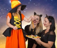 halloween Dwa kobieta w kostiumów czarnych kotach taktuje mała czarownica z cukierkiem Piękna dziewczyna w Halloweenowym kostiumu zdjęcie royalty free halloween Dwa kobieta w kostiumów czarnych kotach taktuje mała czarownica z cukierkiem Piękna dziewczyna w Halloweenowym kostiumu zdjęcie royalty free