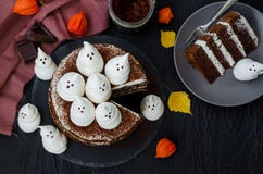Halloween layer chocolate cake with white chocolate cream and meringue ghosts on top.