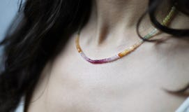 Halsband av m?ngf?rgade och skinande stenar p? halsen av en ung kvinna royaltyfri bild Halsband av m?ngf?rgade och skinande stenar p? halsen av en ung kvinna royaltyfri bild