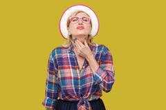Halsen sm?rtar sjukdom eller influensa St?ende av den sjuka moderna stilfulla mogna kvinnan i tillf?llig stil med hatt- och glas? royaltyfri bild Halsen sm?rtar sjukdom eller influensa St?ende av den sjuka moderna stilfulla mogna kvinnan i tillf?llig stil med hatt- och glas? royaltyfri bild