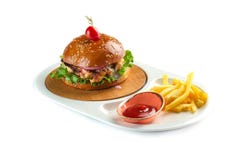 Hamburguesa, patatas fritas y salsa de tomate en una placa oval blanca aislada en el fondo blanco foto de archivo Hamburguesa, patatas fritas y salsa de tomate en una placa oval blanca aislada en el fondo blanco foto de archivo
