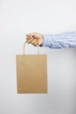 Hand av affärsmannen som rymmer den bruna pappers- påsen royaltyfri bild Hand av affärsmannen som rymmer den bruna pappers- påsen royaltyfri bild