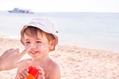 Hand av den caucasian modern som applicerar suncream till henne arkivbild Hand av den caucasian modern som applicerar suncream till henne arkivbild