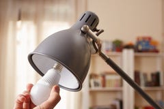 Hand changing a regular light bulb for LED
