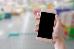 Hand die slimme telefoon met onduidelijk beeldachtergrond houden stock afbeeldingen Hand die slimme telefoon met onduidelijk beeldachtergrond houden stock afbeeldingen