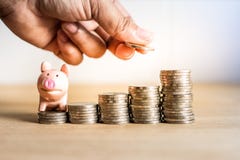 A hand holding coin to saving money for future with piggy bank on stack money,Success of life in future stock image A hand holding coin to saving money for future with piggy bank on stack money,Success of life in future stock image
