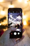 Hand holding mobile smart phone Taking photo of christmas background with bokeh light background stock image Hand holding mobile smart phone Taking photo of christmas background with bokeh light background stock image