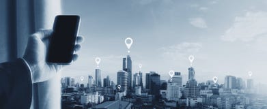 Hand holding mobile smartphone and city view. Mobile phone GPS global positioning system navigation technology stock photo Hand holding mobile smartphone and city view. Mobile phone GPS global positioning system navigation technology stock photo