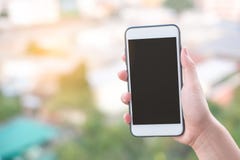 Hand holding smartphone or mobile phone with city building background and copy space. stock photo Hand holding smartphone or mobile phone with city building background and copy space. stock photo