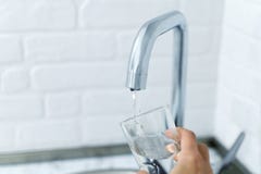 Hand holds the glass, filling it with water from tap. stock image Hand holds the glass, filling it with water from tap. stock image