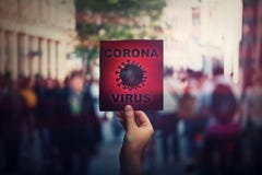 Hand holds red banner warning rapidly spreading Coronavirus on crowded city streets. Deadly Corona virus epidemic outbreak,