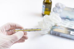 Hand i den medicinska handsken som rymmer en termometer med piller och läkaren arkivbild Hand i den medicinska handsken som rymmer en termometer med piller och läkaren arkivbild