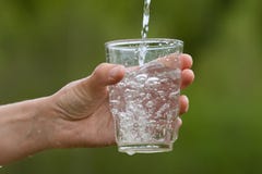 Hand pouring clean natural water into a glass, closeup royalty free stock images Hand pouring clean natural water into a glass, closeup royalty free stock images