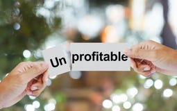 Hand tear wording unprofitable on paper in two pieces stock photography Hand tear wording unprofitable on paper in two pieces stock photography