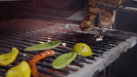 Hand turn piece of salmon fish inside charcoal oven for grilling and also in the tray are lemon, bell pepper and chilli