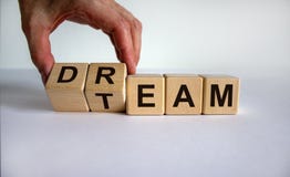 Hand is turning cubes and changes the word `dream` to `team`. Beautiful white background. Business concept, copy space