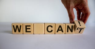 Hand turns a cube and changes the words `we can`t` to `we can`. Beautiful white background. Concept of business vision and