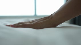 Hand of a woman touches very soft and clean bed linen.