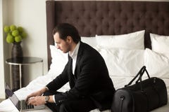 Handelsreiziger die aan laptop in hotelruimte werken stock foto Handelsreiziger die aan laptop in hotelruimte werken stock foto