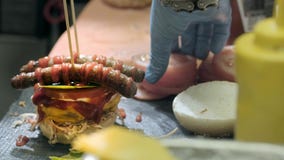 Handen die een hamburger voorbereiden Sluit omhoog mening van het voorbereiden van een rundvleeshamburger bij het festival van he stock footage Handen die een hamburger voorbereiden Sluit omhoog mening van het voorbereiden van een rundvleeshamburger bij het festival van he stock footage